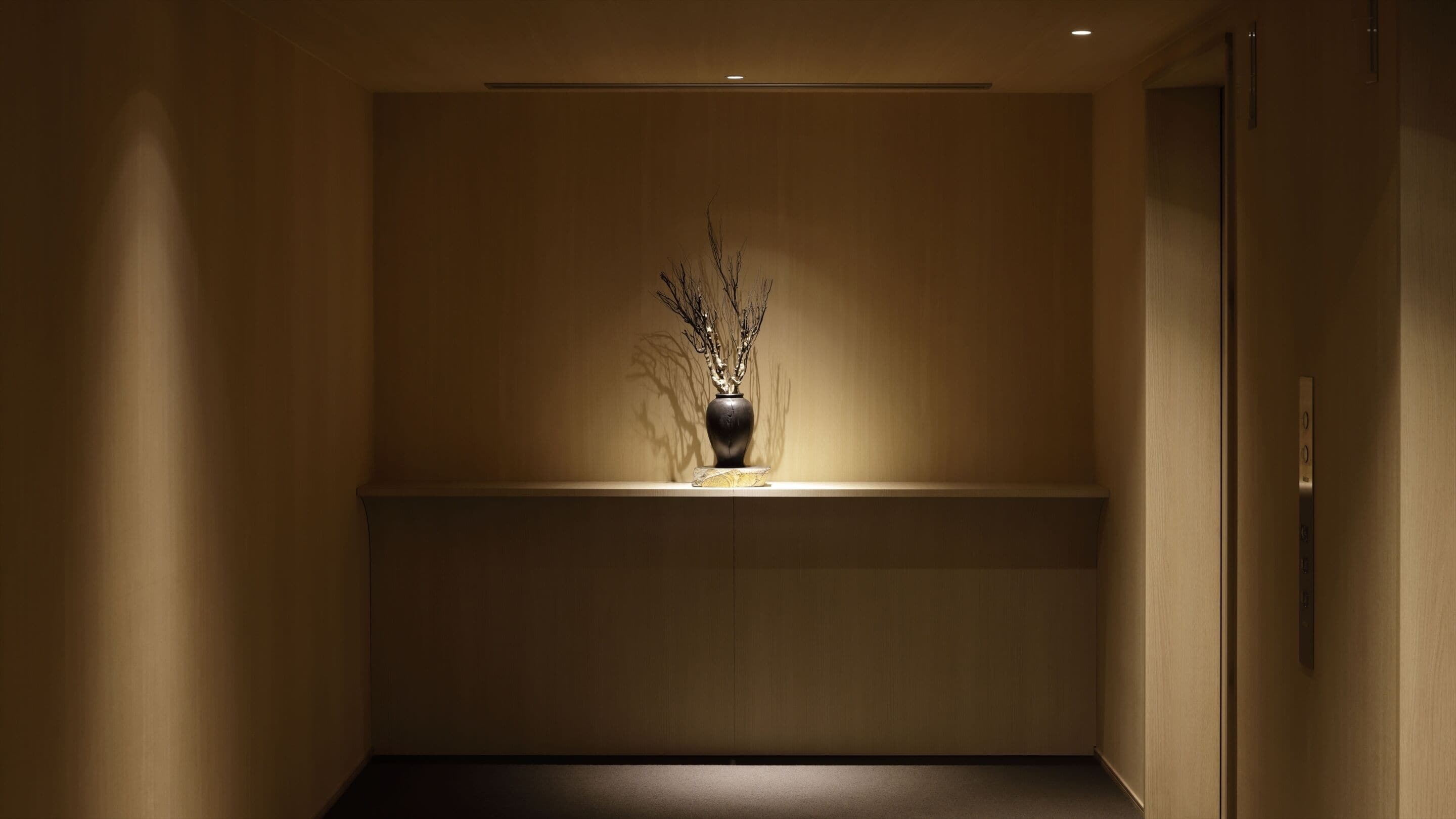A hallway with a vase of branches on a shelf.