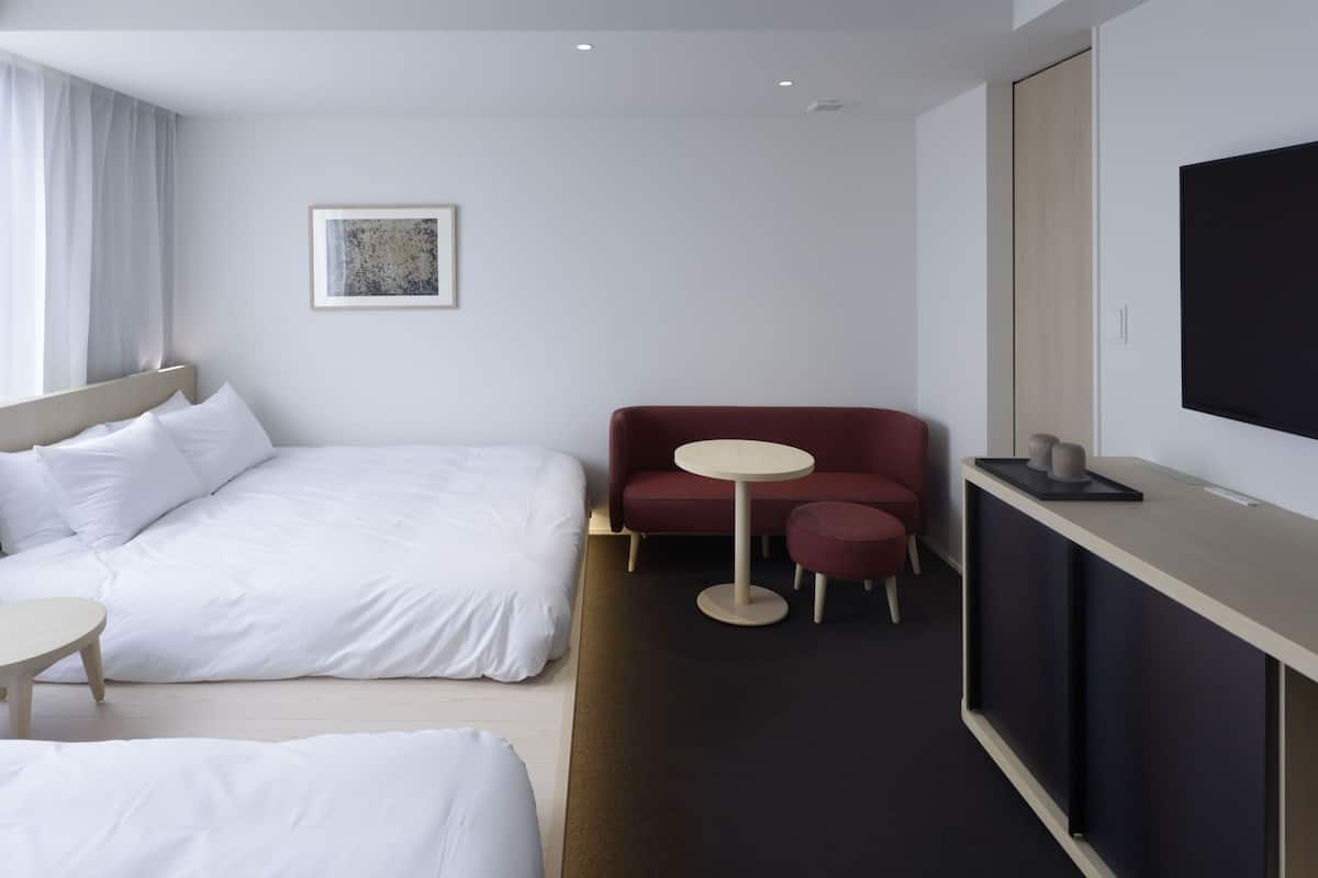 Habitación de hotel con cama, escritorio, silla, televisión y una mesita.