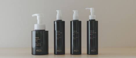 Four black bottles of skincare products with pumps, labeled for different skin types and purposes, arranged on a surface.