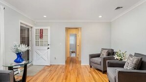 A living room with hardwood flooring, a grey sofa set, and a blue vase on a glass table. - Perfect summer getaway in Hampton Bays. Last 2 weeks of Summer, still available! (Hampton Bays)