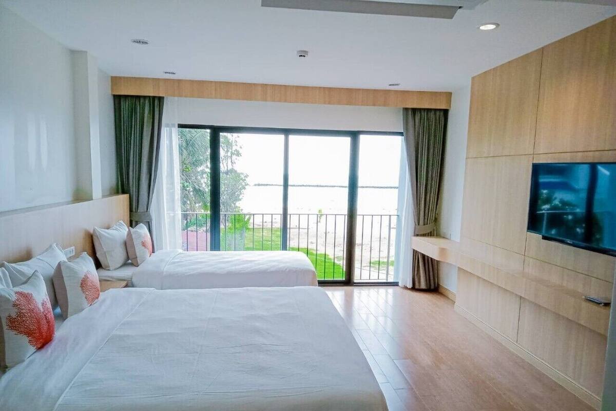 A hotel room with two beds, a balcony, and a TV.