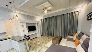 A modern living room with a sofa, a coffee table, and a flat-screen TV mounted on a white wall. - Ibex Meanwood suite (Lusaka)