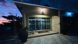 A modern house with a hexagonal tiled entrance, a large potted plant, and a metal gate. - Ibex Meanwood suite (Lusaka)