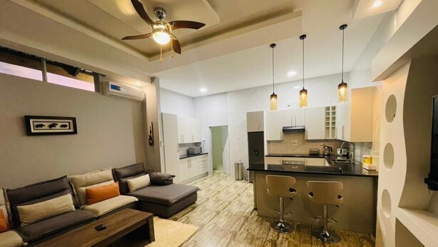 A modern living room with a sofa, a coffee table, and a ceiling fan. - Ibex Meanwood suite (Lusaka)
