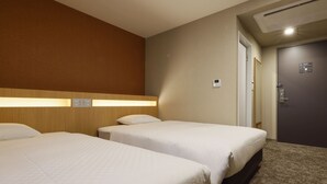 Et hotelværelse med to senge, et træhovedgærde, tæppe på gulvet og en dør med lås.