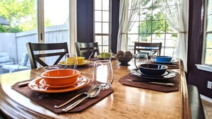 Una mesa de comedor puesta con platos, tazones, vasos y cubiertos.