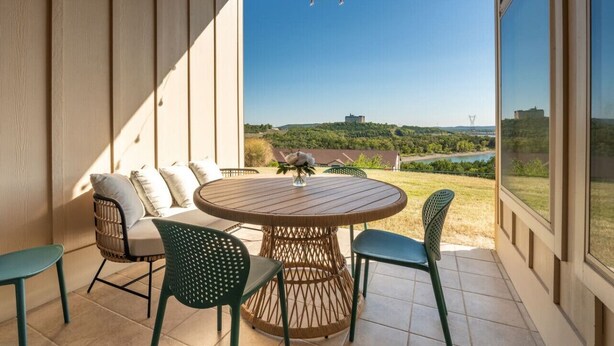 A covered patio with a round table and chairs, overlooking a scenic landscape.