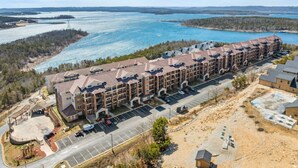 A multi-story hotel with a parking lot and a view of a lake.