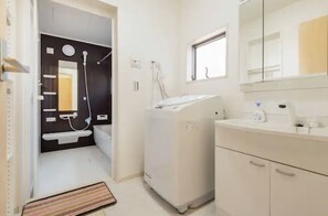 Een badkamer met een wit wastafel, spiegel en een witte wasmachine.