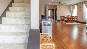 A spacious living area with a wooden floor, a staircase, and a dining area with wooden chairs and a table. - Remodeled historic family home w/ full kitchen & garage parking (St. Louis)