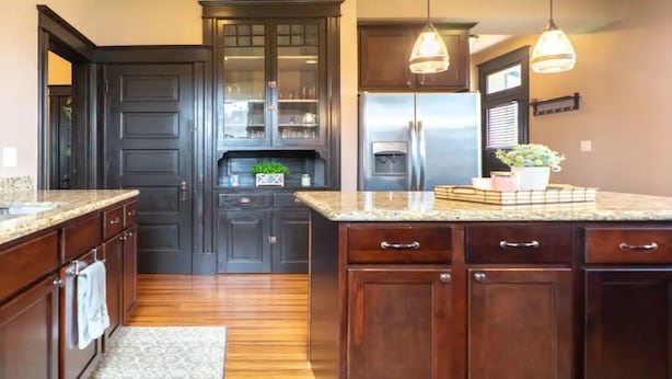 A kitchen with dark wooden cabinets, a stainless steel refrigerator, and pendant lighting. - Remodeled historic family home w/ full kitchen & garage parking (St. Louis)