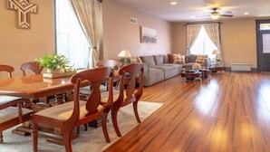 A spacious living room with a wooden floor, a dining area with wooden chairs and a table, and a sofa set. - Remodeled historic family home w/ full kitchen & garage parking (St. Louis)