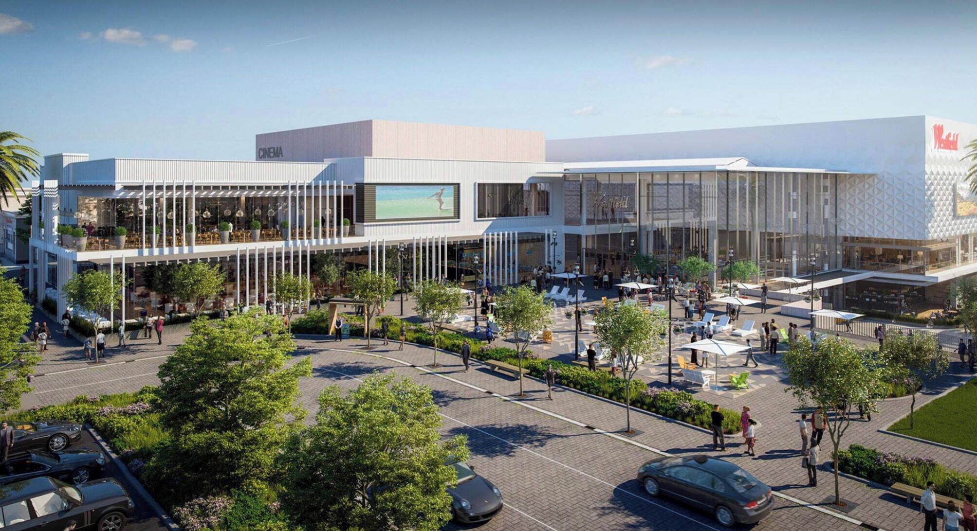 A modern building with a cinema, outdoor seating, and a parking area.