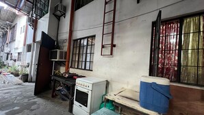 A narrow alleyway with a white building, a ladder, a window with metal bars, and a blue cooler on a table. - King Henrys Transient House (Bantay)