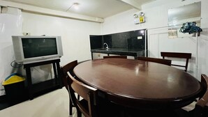 A compact kitchen with a dining table, chairs, a television, and a refrigerator. - King Henrys Transient House (Bantay)