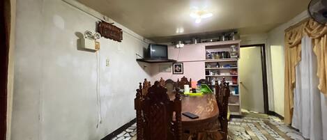 Comedor con una mesa redonda, sillas, un televisor en un estante y un piso con diseño.