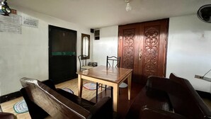 A dining area with a wooden table and chairs, a black door with a green stripe, and a decorative wooden door with intricate carvings. - King Henrys Transient House (Bantay)