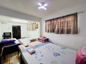A small, well-lit room with two beds, a desk, and a television. - King Henrys Transient House (Bantay)