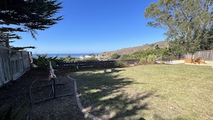 A backyard with a lawn, a hose, and a wooden fence. - Stunning ocean views close to beach and SF (Pacifica)