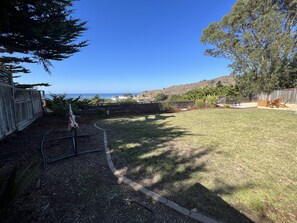 Relax in a serene ocean-view backyard with a well-maintained lawn and comfortable outdoor seating.