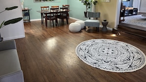 A dining area with a wooden table and chairs, a potted plant, and a round patterned rug on the floor. - Stunning ocean views close to beach and SF (Pacifica)