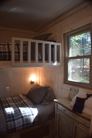 Ein Holzhüttenraum mit einem Bett, einem Fenster und einem Schrank.