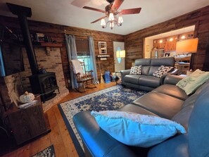A cozy living room with a fireplace, leather sofa, and a ceiling fan.