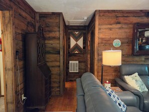 A room with wooden walls, a black leather sofa, a lamp, and a decorative mirror. - The Linville Community, a restful retreat watch the changing colors.  (Newland)