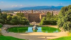 A historic building with a fountain, surrounded by greenery and a view of a cityscape. - Podere Apostoli (Bagno a Ripoli)