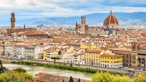 A panoramic view of a historic city with prominent architecture, including a large dome and towers, along a river. - Podere Apostoli (Bagno a Ripoli)