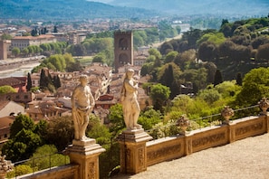 A stone balustrade with statues, a tower, and a cityscape in the background.