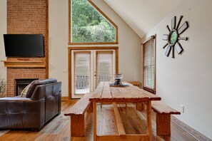 Ein Wohnzimmer mit Kamin, einer Ledersofa, einem Holzesstisch und einem großen Fenster mit Jalousien.