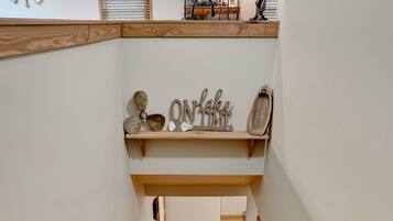 A wooden staircase with a handrail, leading to a landing with a shelf displaying decorative items.