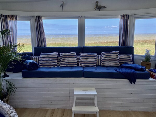 A room with a blue sofa, striped pillows, and a view of the ocean.