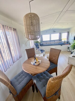 Ein Essbereich mit einem runden Holztisch, blauen Sitzgelegenheiten mit Polsterung und einer hängenden Lampenschirm aus Gewebe.