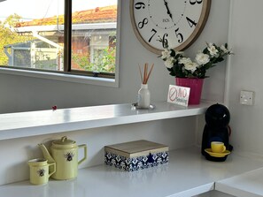 A kitchen counter with a clock, a 'No Smoking' sign, a potted plant, a coffee maker, and a teapot.