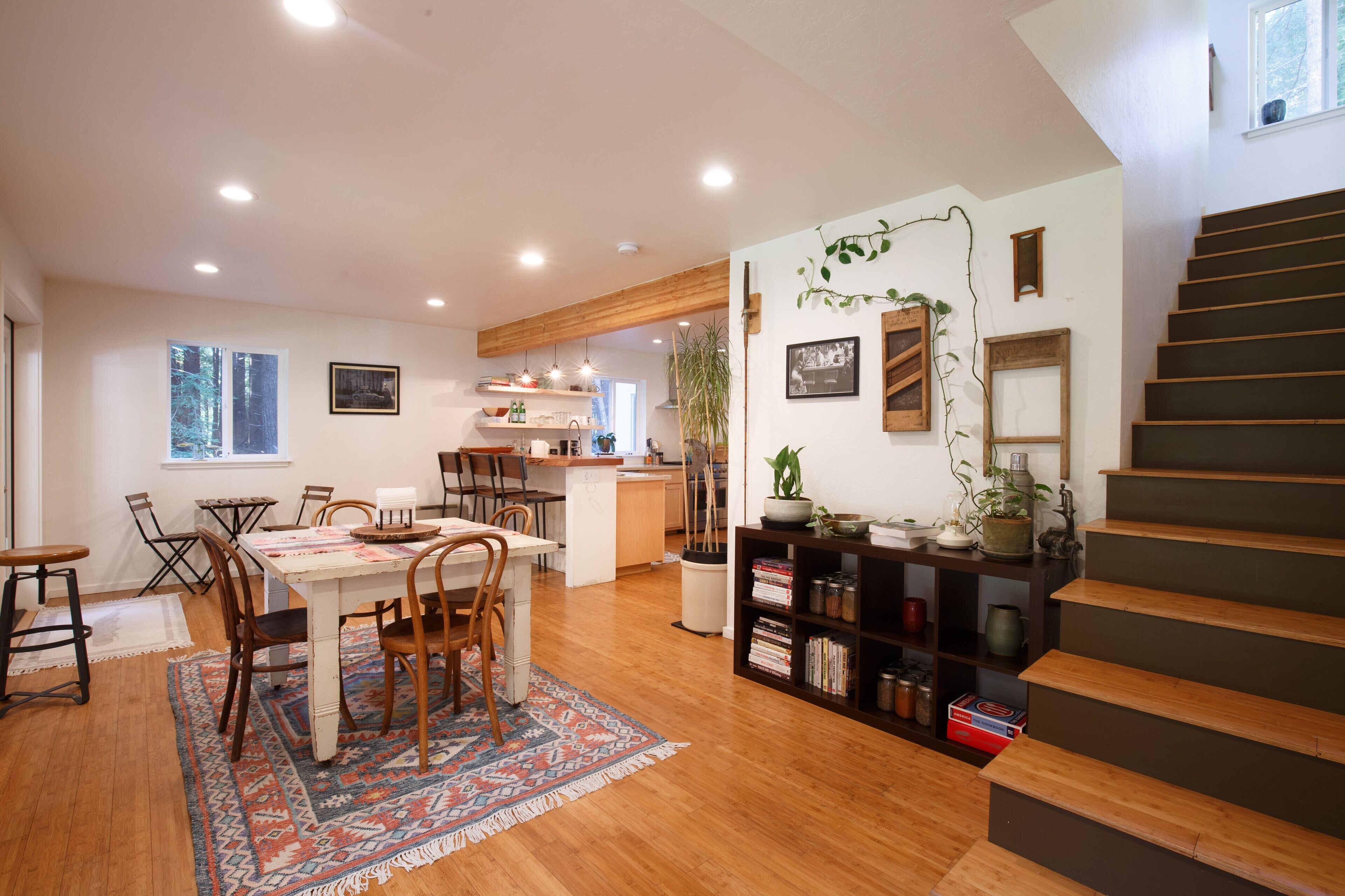 Una cocina amplia con suelo de madera, un comedor con alfombra estampada y una escalera con acabado oscuro.
