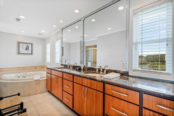 A modern bathroom with a large mirror, dual sinks, and a bathtub.