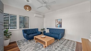 A living room with two blue sofas, a wooden coffee table, patterned rug, and a ceiling fan.