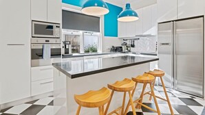 Une cuisine moderne avec des meubles blancs, un plan de travail noir et un îlot central doté de tabourets en bois.