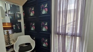 A room with a black wall adorned with floral and bird artwork, a white chair, a patterned rug, and a window with purple curtains. - 2-bed House in the Heart of Woodhouse, Leeds (Leeds)