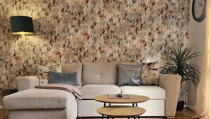A living room with a sofa, a coffee table, a lamp, and a clock on the wall. - 2-bed House in the Heart of Woodhouse, Leeds (Leeds)