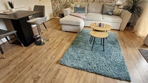 A living room with a sofa, a coffee table, a dining table with chairs, and a patterned wallpaper. - 2-bed House in the Heart of Woodhouse, Leeds (Leeds)