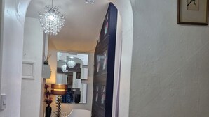 A hallway with a white radiator, a patterned rug, a white chair, and a chandelier. - 2-bed House in the Heart of Woodhouse, Leeds (Leeds)