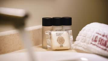 A bathroom with a white towel, a bottle of soap, and a bottle of lotion.
