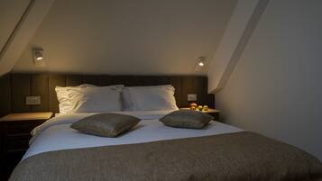 A bedroom with a bed, pillows, a nightstand, and a wall-mounted light fixture.