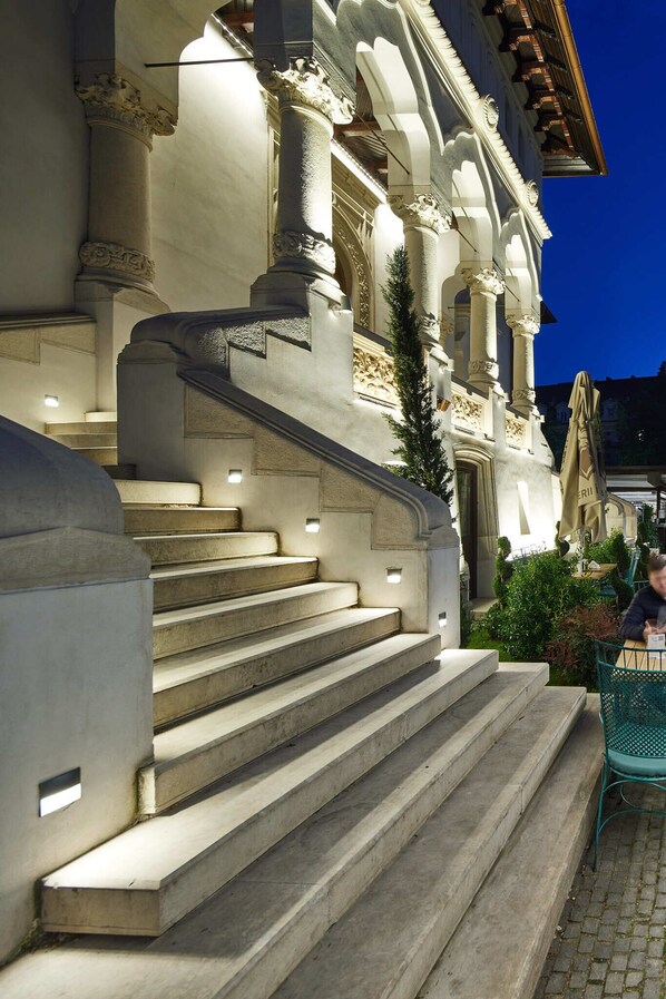 Una gran escalera conduce a un edificio con columnas ornamentadas y un balcón.