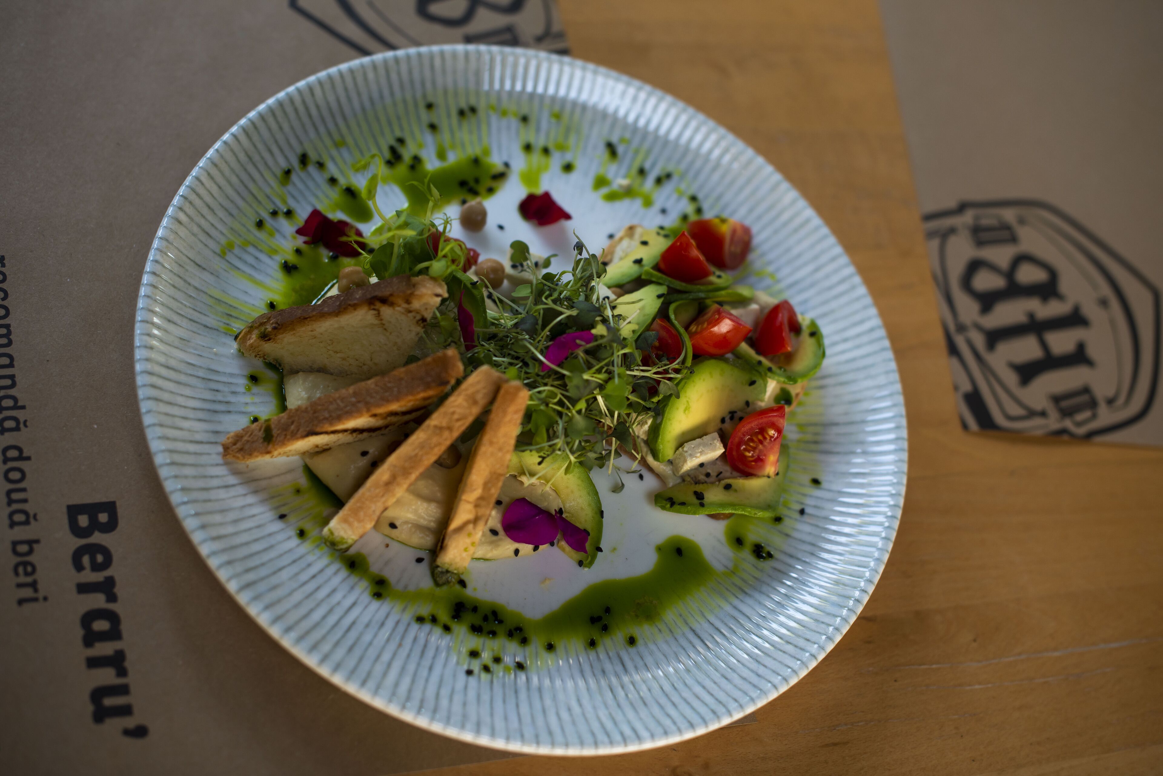 A plate of food with various vegetables and a green sauce on a white plate.