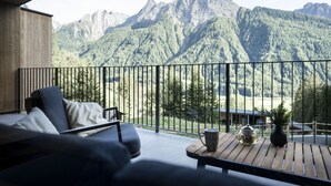A balcony with a sofa and a table, overlooking a mountainous landscape.