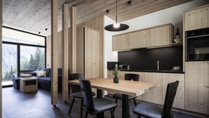A modern kitchen with wooden cabinets, a dining table, and black chairs.